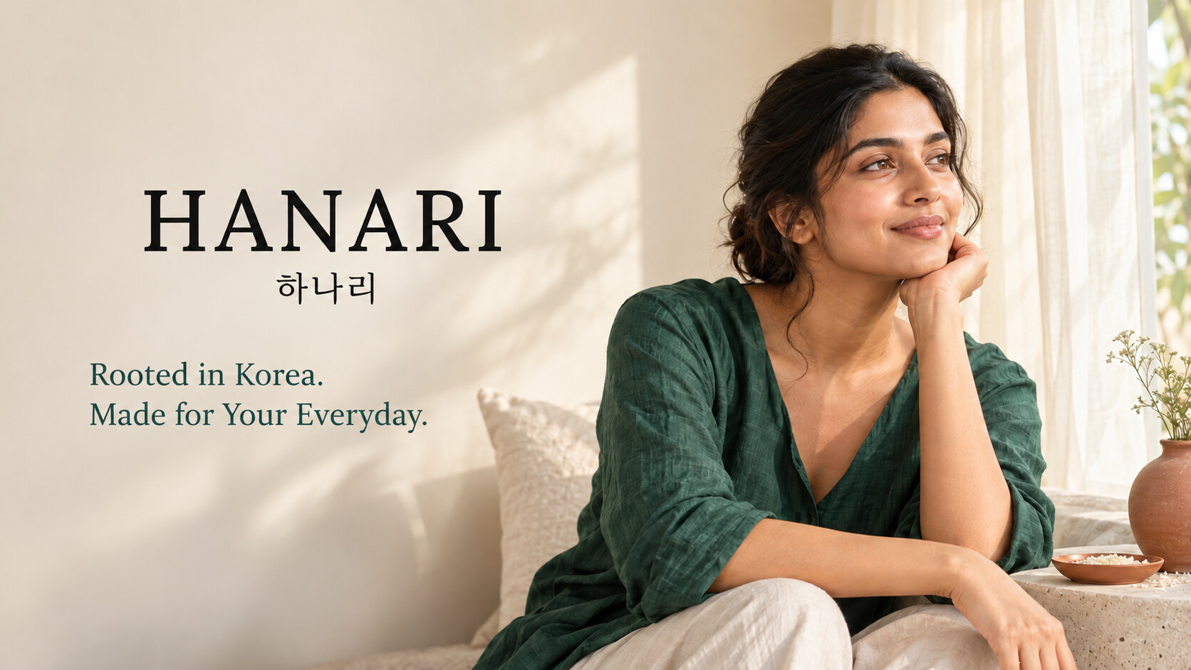 Concept render for HANARI: a woman resting her chin on her hand by a sunlit window, beside the words “Rooted in Korea. Made for Your Everyday.”
