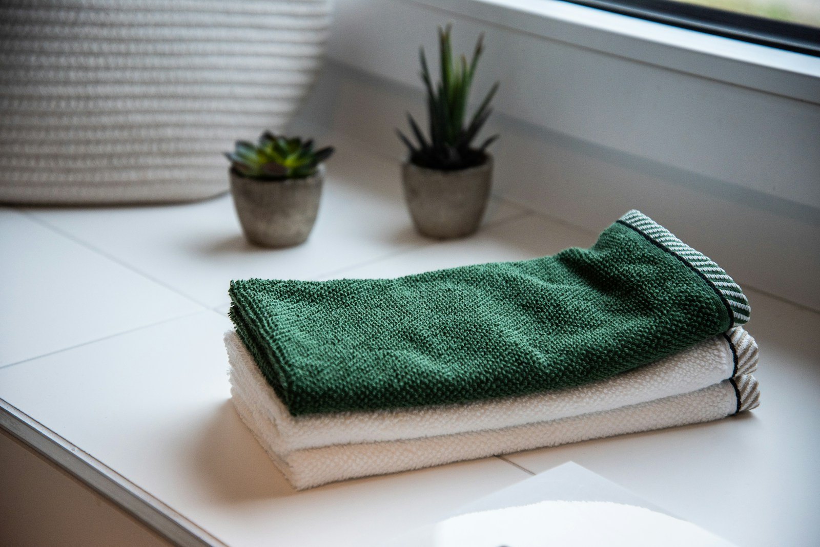 Folded towels beside small potted plants