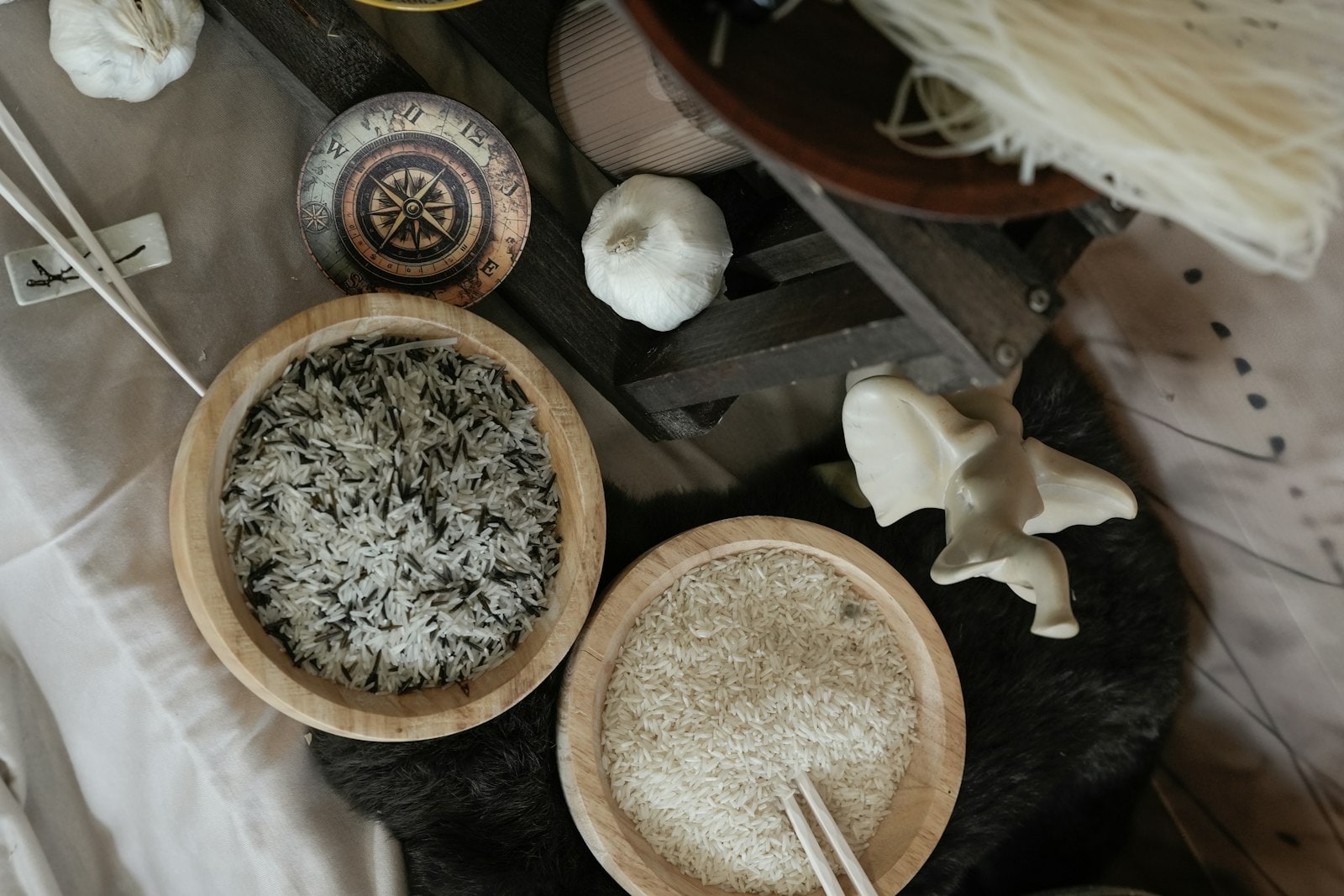 लकड़ी के दो कटोरों में कच्चे चावल और चॉपस्टिक